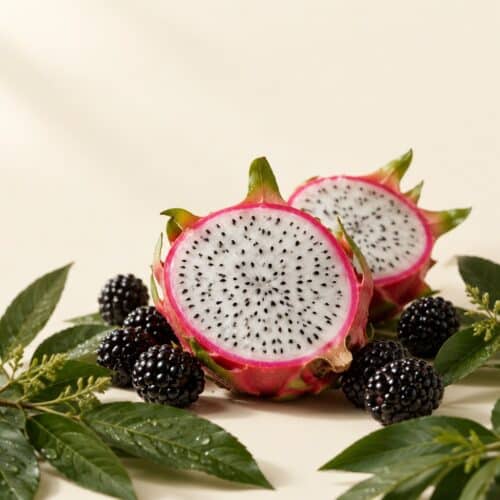 Drachenfrucht und Brombeeren auf cremefarbenem Hintergrund